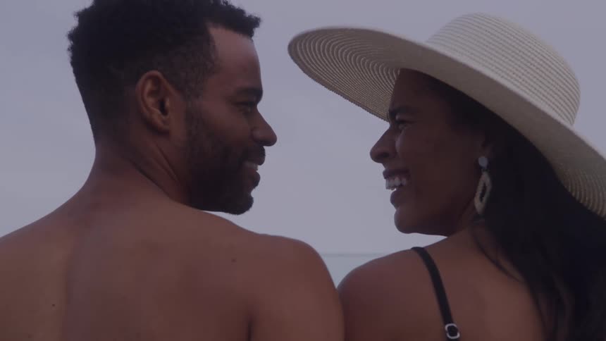A smiling couple stands close together gazing at each other outdoor at dusk