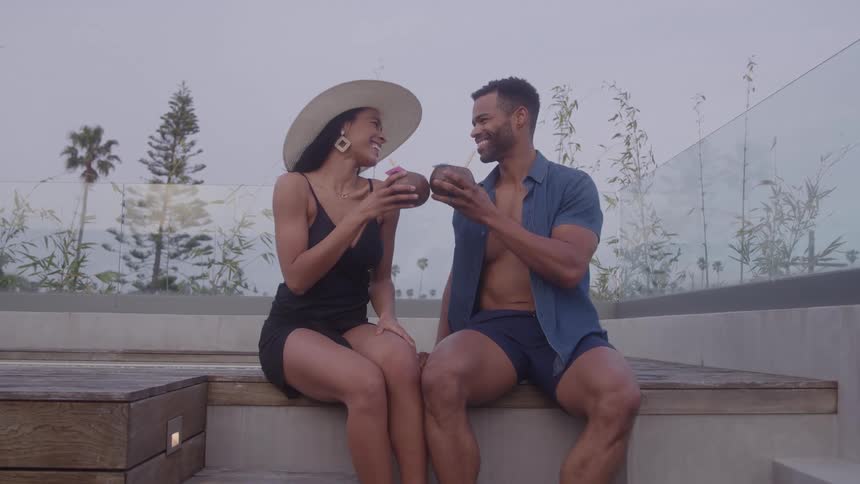 The man and woman toast their drinks while on vacation