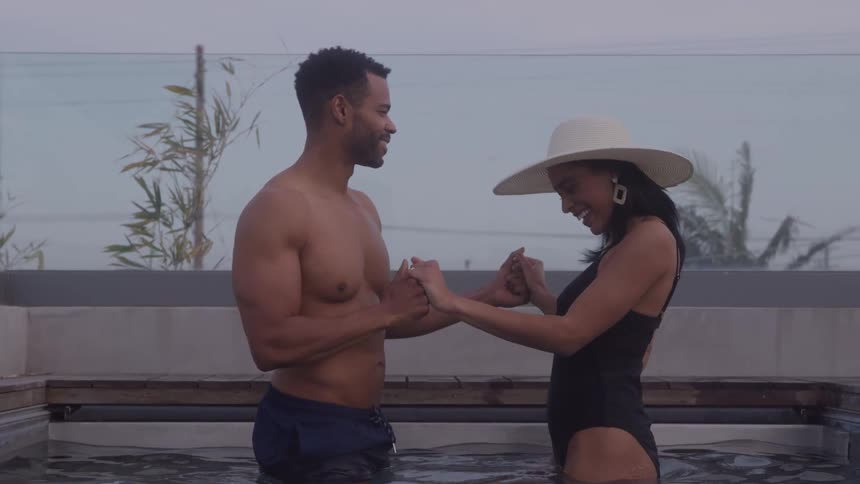 A joyful couple dances and smiles in a pool at twilight