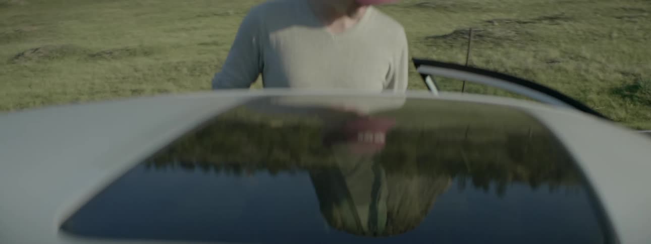 Man smokes a cigarette standing outside of a car