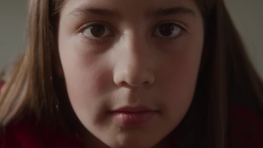 A very tight closeup focuses entirely on the eyes and nose of a young girl she is staring intensely directly at the camera with a serious or inquisitive expression