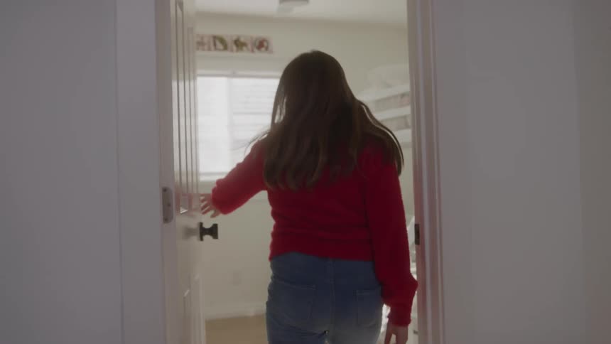 A young woman walks into her bedroom slamming the door behind here as she is followed by the camera