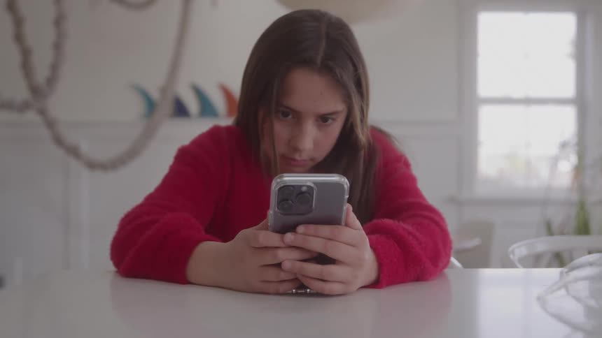 Girl attentively looks at phone in a welllit and decorated indoor setting