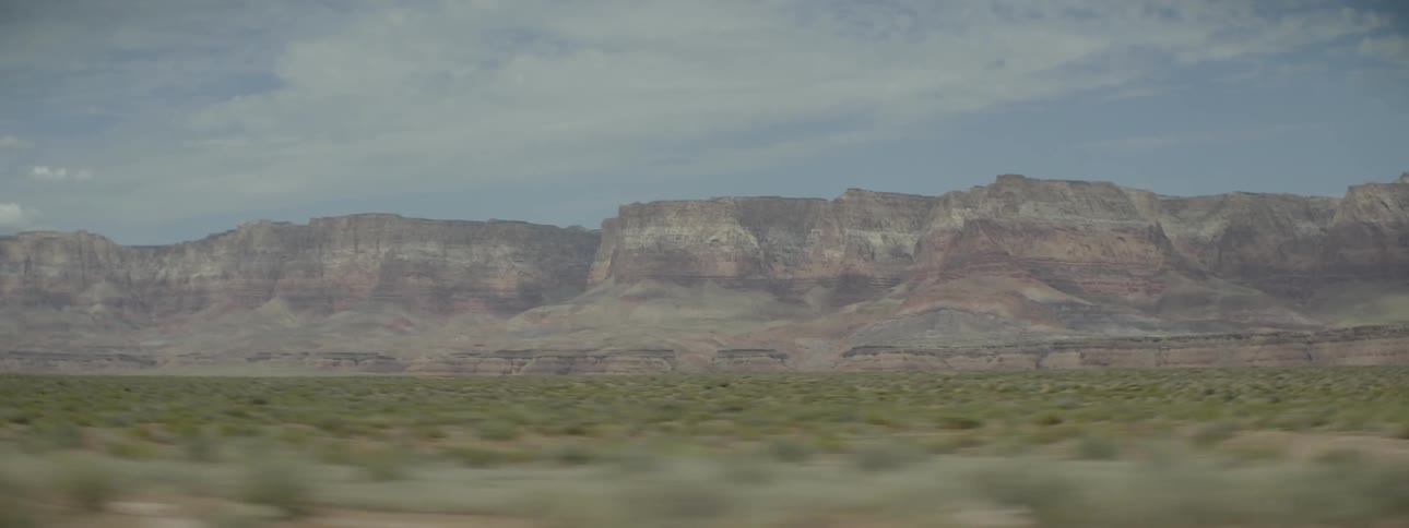 A long green field leads to a mountain ahead