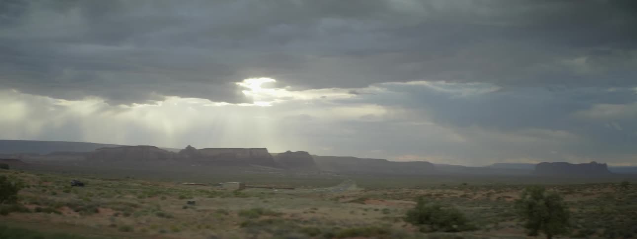 A truck is traveling over the field ahead on a cloudy day