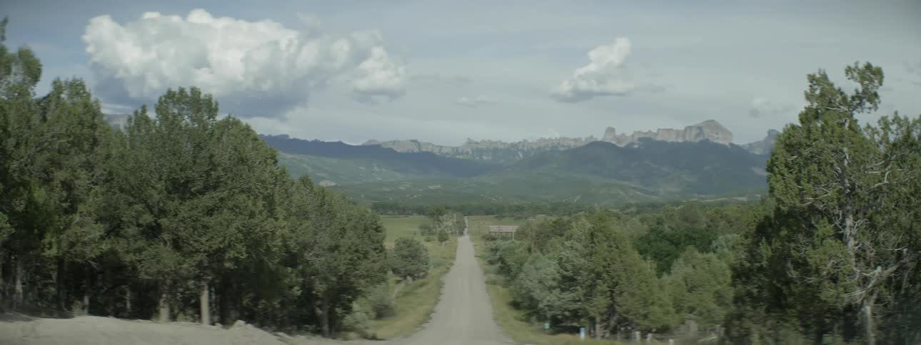 A small road goes downhill towards a mountain