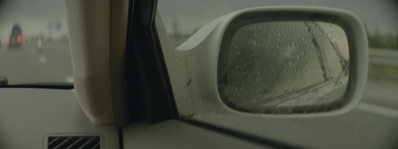 Wet right side mirror of car traveling on freeway