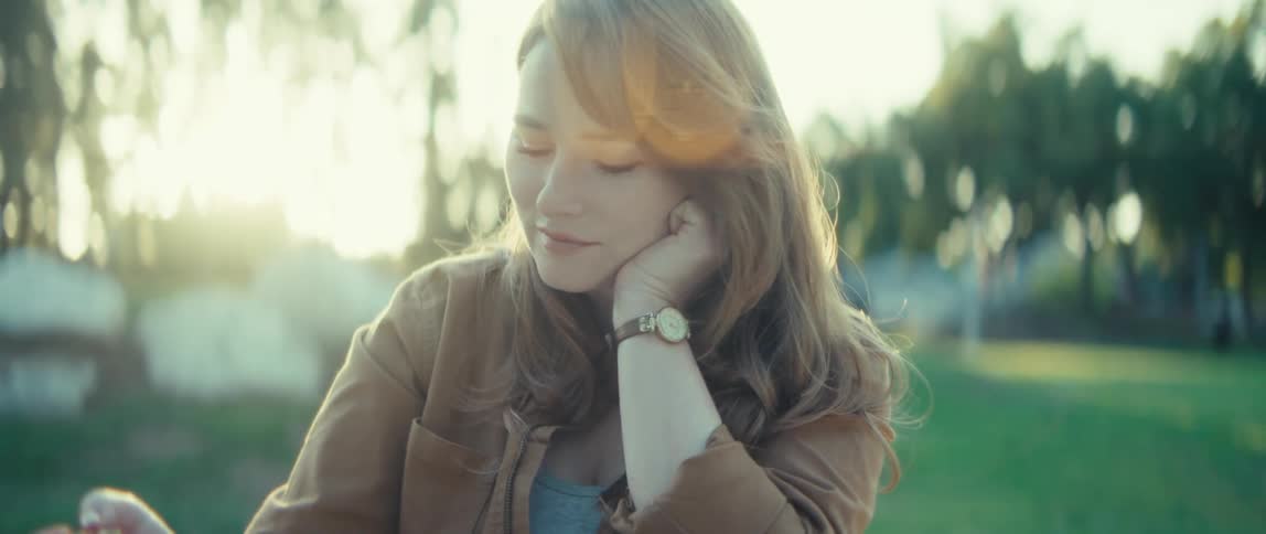 A woman paints while sittingin a park under soft golden sunlight
