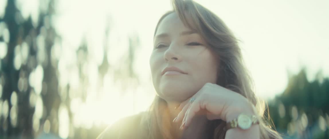 Woman with a serene expression gazing into the distance under gentle evening light