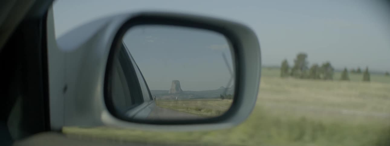The sideview mirror of a moving vehicle is shown