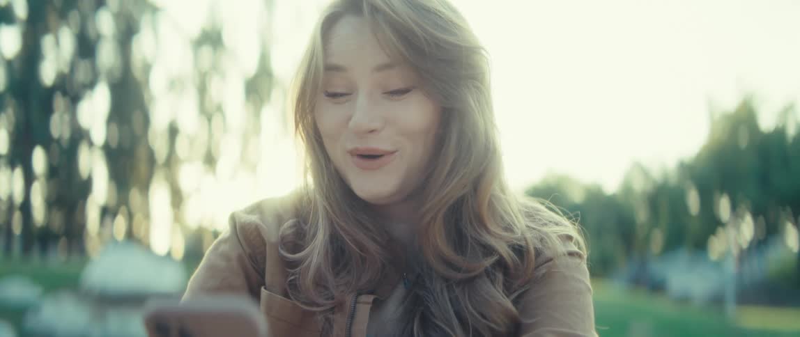 The woman is shocked at her cell phone and begins laughing
