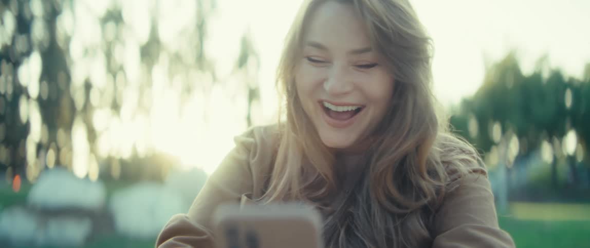 The woman is shocked and happy when she looks at her cell phone
