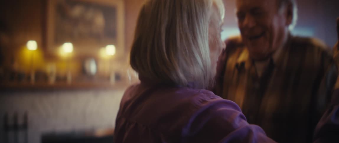 An elderly couple dancing happily in the middle of the living room