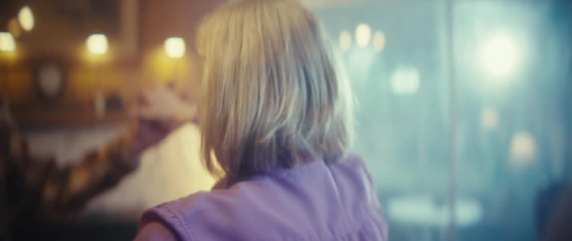 A closeup shot focuses on an elderly couple dancing in a dimly lit cozy living room they are smiling and embracing as they move gently to the music with the light creating a warm nostalgic atmosphere