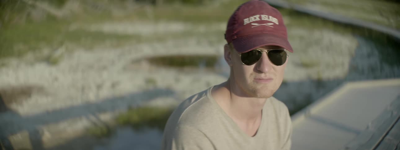 A man is sitting outside wearing sunglasses