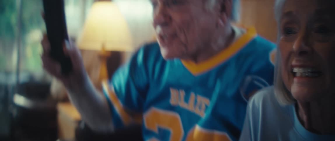 Elderly couple cheering and smiling while watching tv