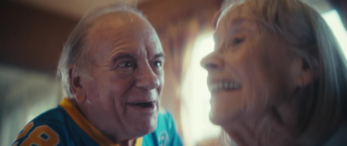 Elderly couple smiling and sharing joyful looks indoors
