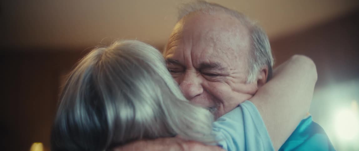 A man smiles as he hugs a woman