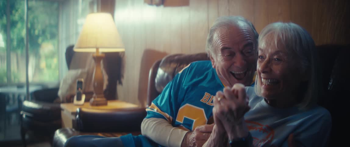 A man and woman are clapping and celebrating on a couch