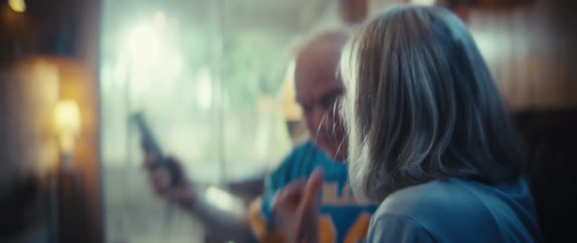 Elderly people embrace smiling in indoor setting with wooden wall and lit lamp in the background