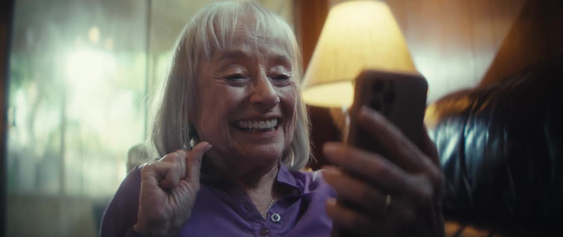 The woman smiles and waves at her cell phone