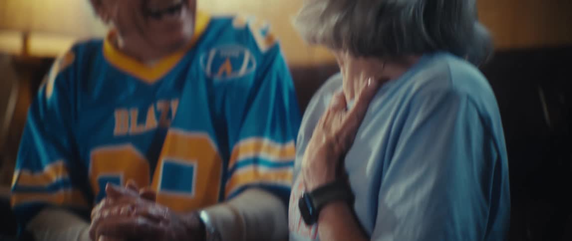 The man and woman cheer and hug as they watch a sports game