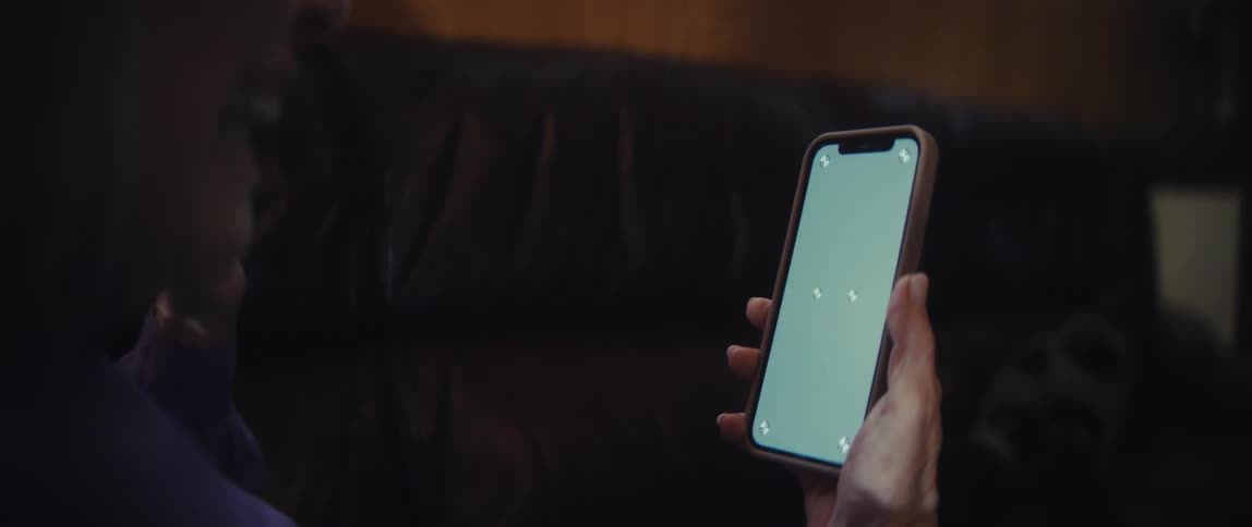 An elderly woman holding a cellphone with one hand and touching the screen with the other