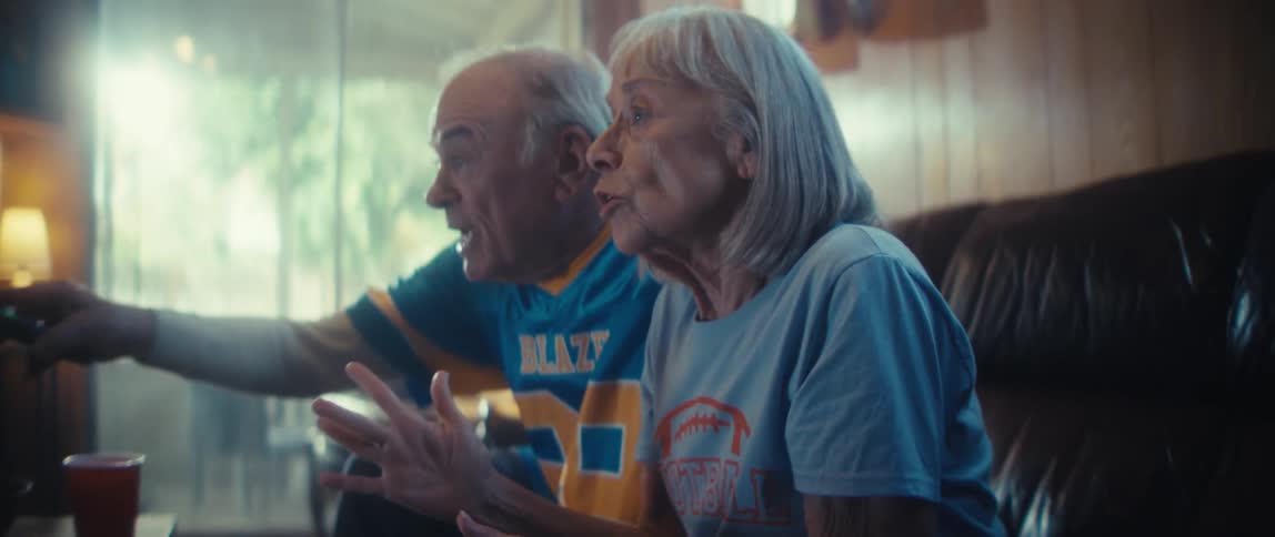 A man and woman are cheering and celebrating as the sit together on a couch