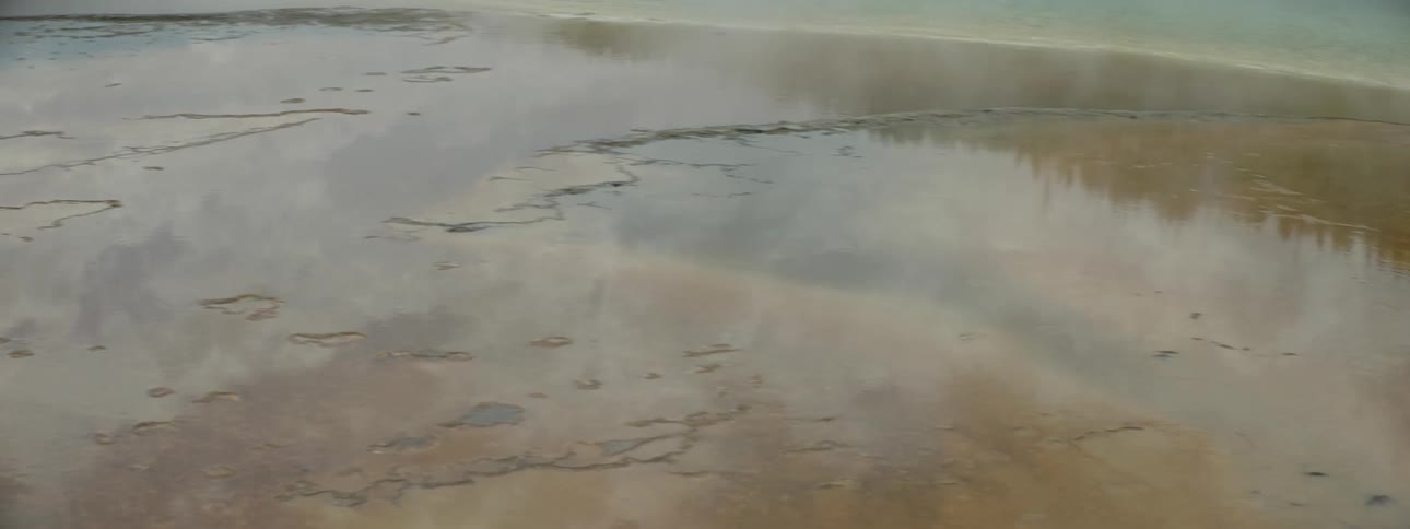 Steam hovers over a shallow body of water