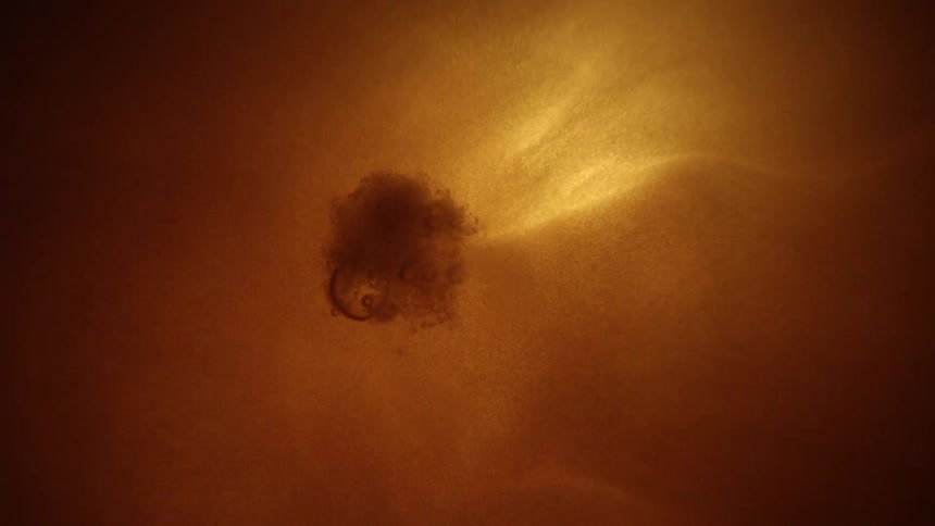 Glowing spherical object with uneven surface emits light amid orang
