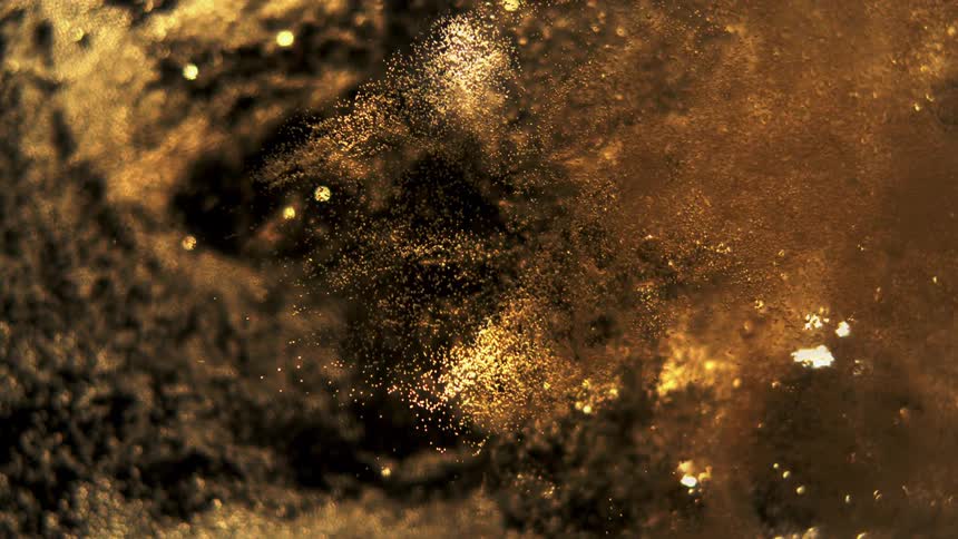 A stream of liquid gold swirls and shifts forming bubbles as it moves