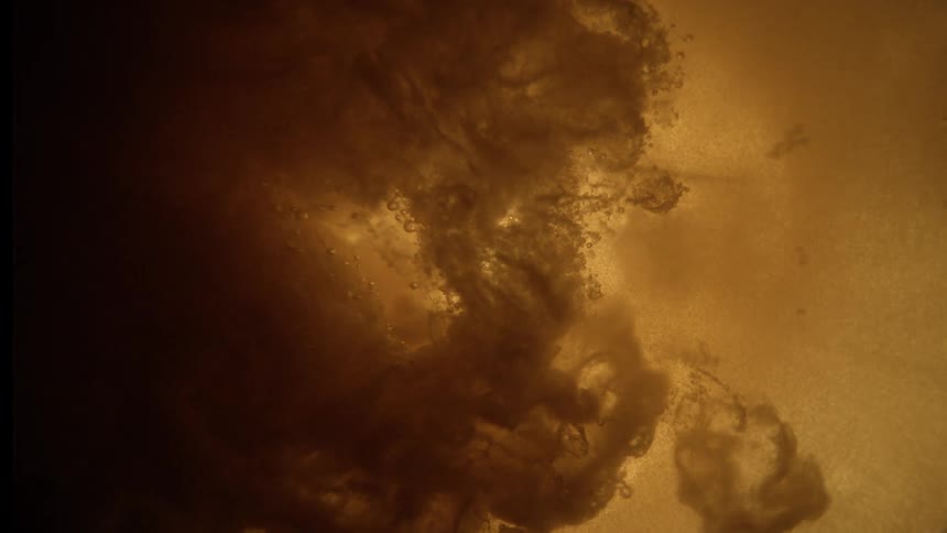 Dense formation in golden and brown tones reveals a turbulent pattern lit from behind