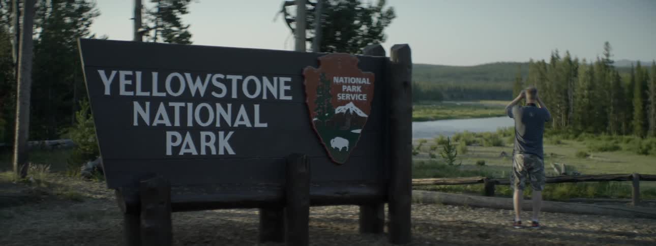 Man taking photographs near yellowstone national park sign