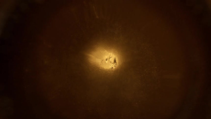 Dark liquid with light spiral pattern in center forming whirlpool effect