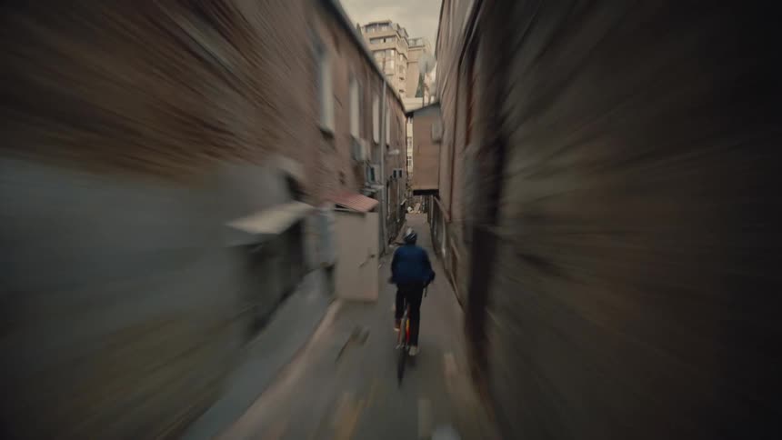 The video is a fastpaced firstperson view following a person riding a bicycle through a very narrow alleywaythe walls on either side are made of aged stone and brick creating a dramatic confining tunnel effect as the cyclist quickly moves forward