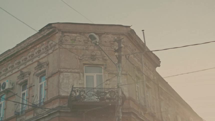 Red light appears in front of old building with iron balconies and weathered facade