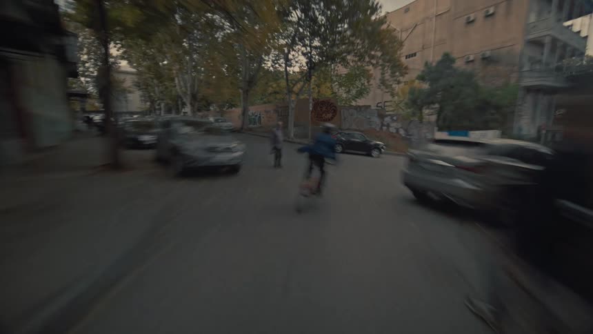 A person wearing a helmet cycles in the middle of the street at midday riding around the neighborhood