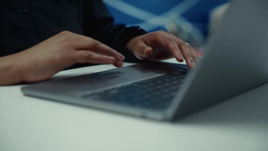 A man is sitting in front of a laptop and typing