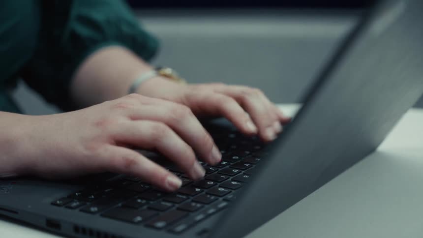 Hands type on black keyboard with red pointer as wrist displays lightcolored watch