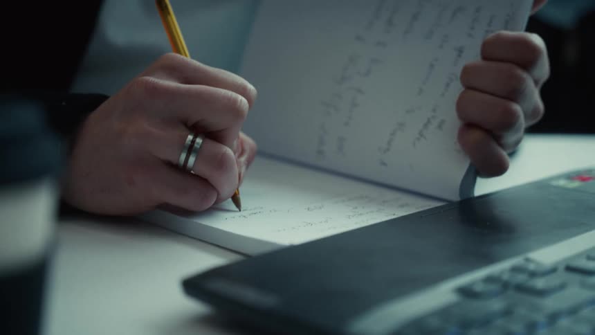 A person writes in a notebook before typing on a laptop