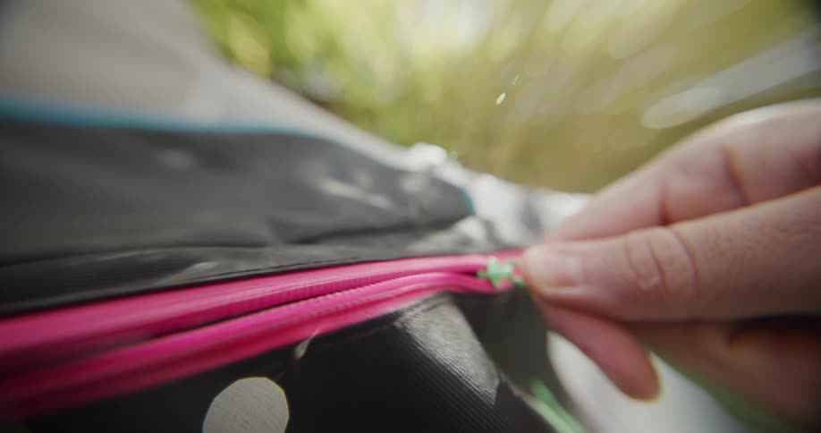 Hand opening the pink zipper of a black bag