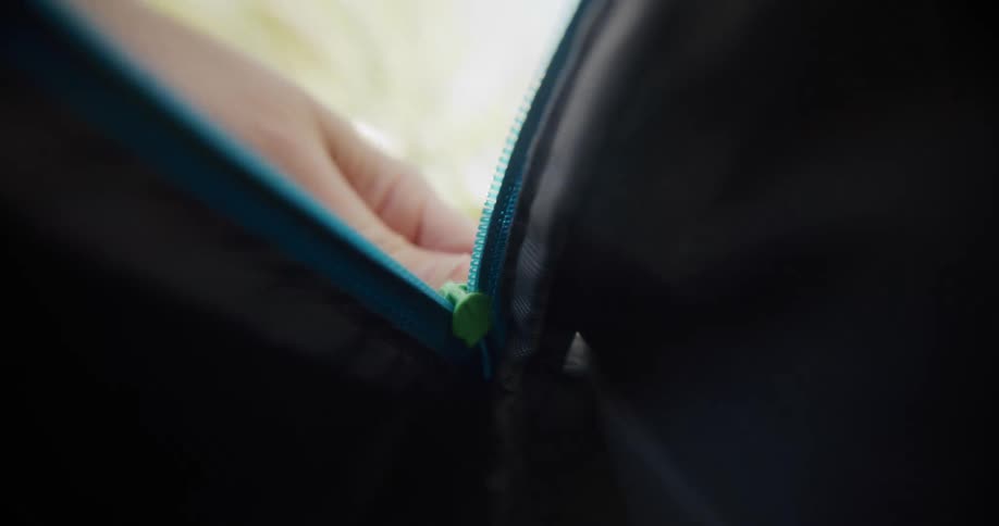 A person is unzipping a blue zipper on a bag