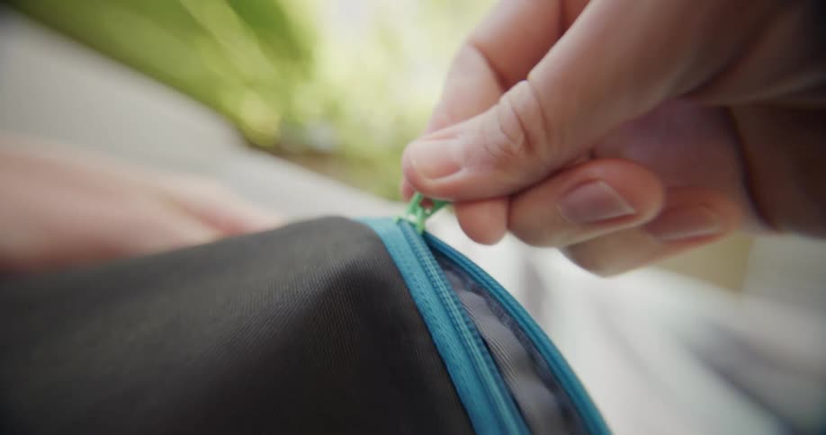 Blue zipper being closed on a black bag