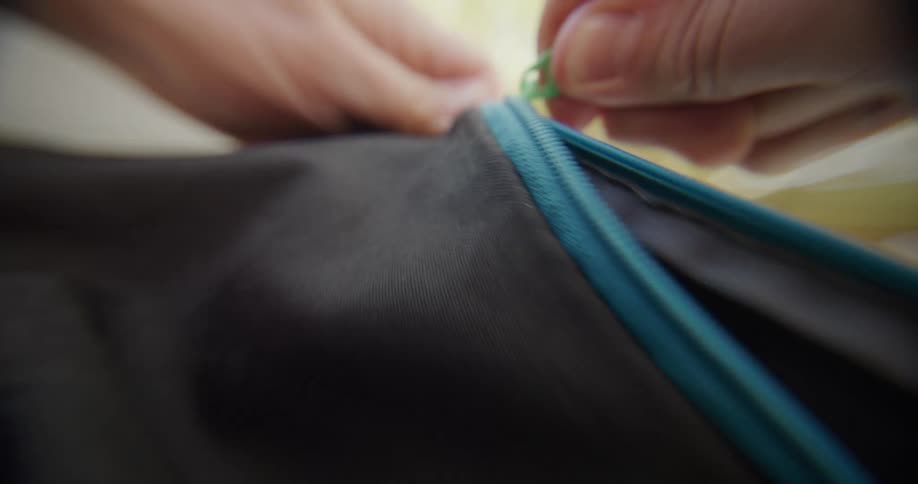 Close up of a person zipping up a backpack outdoors during daytime