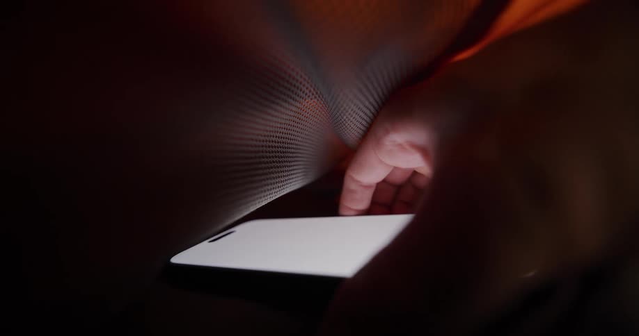 Hand reaches for lit device inside dark compartment with fabric texture