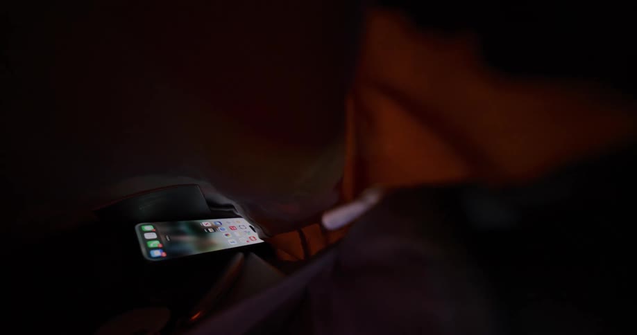 Smartphone displays home screen on soft surface surrounded by fabric in gently lit setting