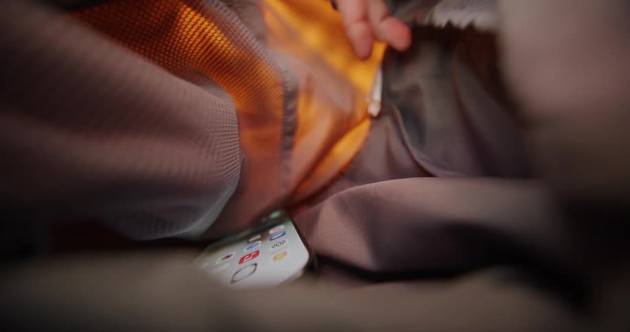 Hand reaches for lit phone inside backpack with fabric and mesh compartments