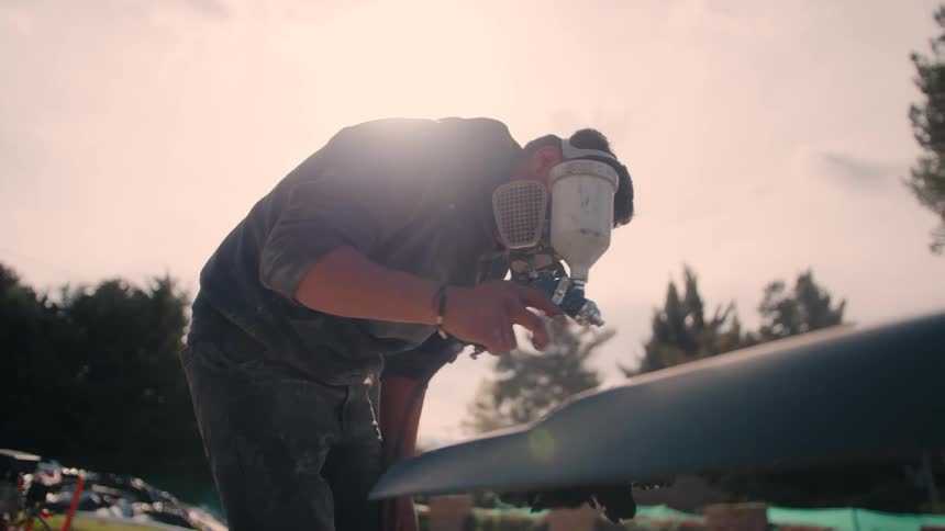 The man carefully spray paints the car