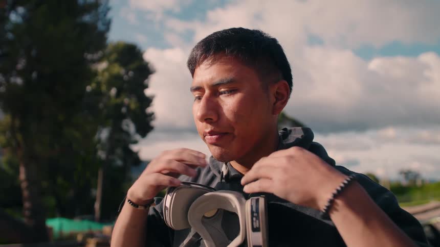 Man standing outdoors on a cloudy day removes his respirator mask