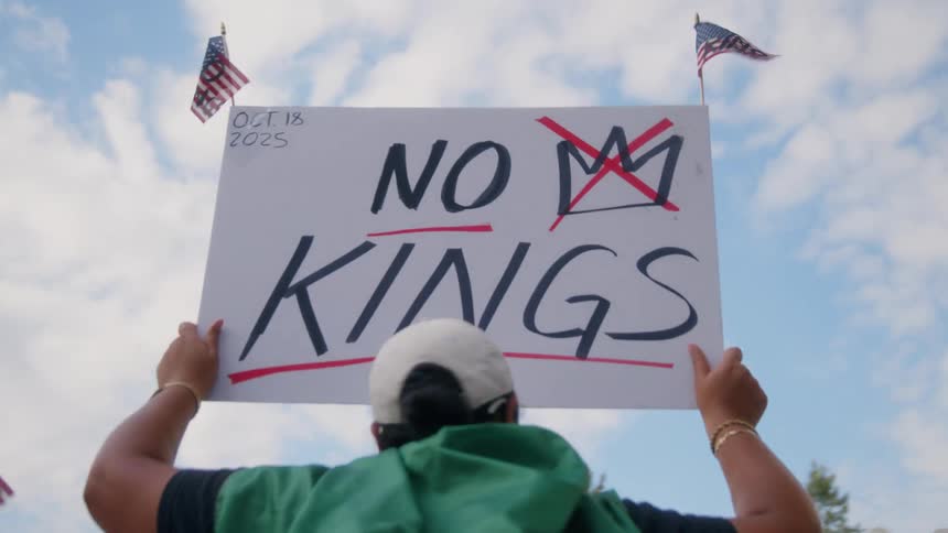 A female protestor is holding a sign stating No Kings above her head